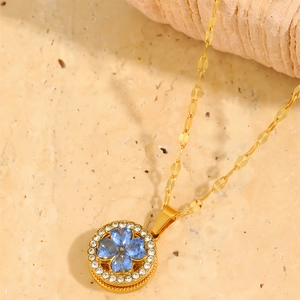 Macro shot of a spinning four-leaf clover necklace with blue crystals and gold plating