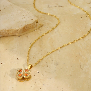 Detail of gold clover necklace featuring orange zircon stones and pavé set crystals
