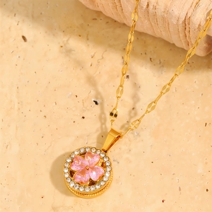 Detail of rotating four-leaf clover crystal pendant on golden titanium necklace