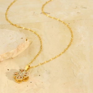 Macro shot of gold four leaf clover necklace with pink gemstone and white zircon stones