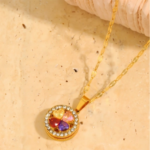 Macro shot of gold pendant featuring four heart-shaped zircons and white diamond border