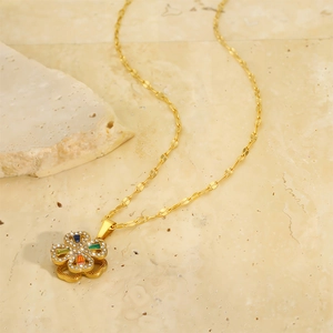 Detailed macro shot of a golden spinning clover pendant necklace on a stone surface