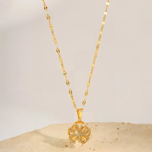Macro shot of gold four-leaf clover pendant with sparkling zircon diamonds on tile chain