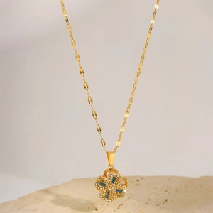 Macro shot of gold-tone four-leaf clover pendant with blue and white zircon inlay