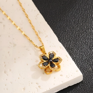 Nahaufnahme der goldenen Blumenkette mit schwarzem Zirkon und Kristallen auf Steinplatte