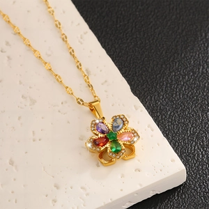 Detailansicht der goldenen Blumenkette mit fünf farbigen Zirkonia auf Steintextur