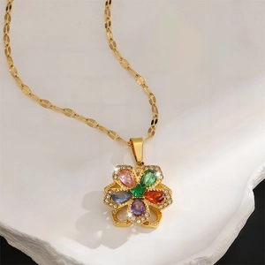 Nahaufnahme des goldenen fünfblättrigen Blumenanhängers mit bunten Zirkonsteinen auf Stein