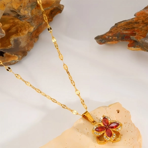 Dettaglio della collana a quadrifoglio dorata con petali rossi e piccoli zirconi
