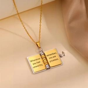 Detail of book-shaped pendant engraved with motivational quote on polished steel surface