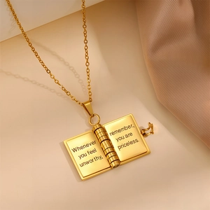 Detail of gold book locket necklace with engraved inspirational message inside
