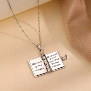 Detail of book-shaped titanium steel pendant with engraved message for daughter