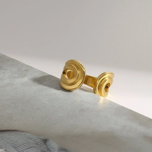 Detalle de un anillo de acero de titanio dorado con un moderno diseño escultórico de doble espiral