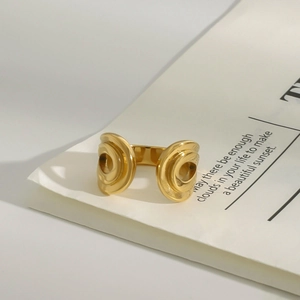 Detalle de un anillo abierto de acero inoxidable dorado con diseño de espiral moderna