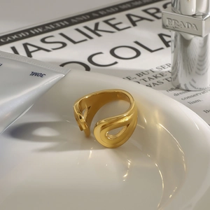 Vista detallada de un anillo abierto de acero de titanio dorado sobre plato de porcelana blanca