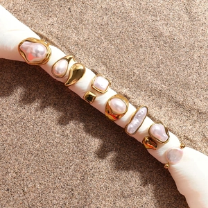 Bagues vintage françaises en acier doré avec perles baroques posées sur le sable de plage