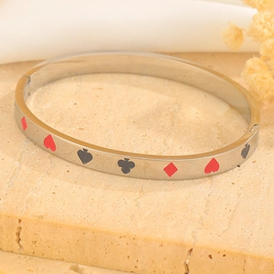 Detail of titanium steel bangle featuring poker suit motifs on natural stone background