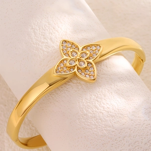 Detailed close-up of a gold-plated clover bangle with inlaid sparkling white crystals