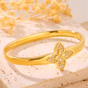 Detailed view of golden stainless steel clover bracelet with sparkling inlaid crystals
