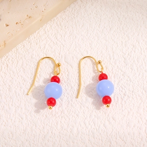 Boucles d'oreilles rétro en acier titane avec agate rouge et perles bleu clair sur marbre