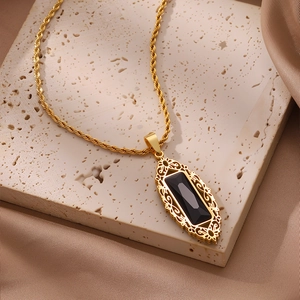 Detalle del collar de cadena trenzada dorada vintage con colgante de gema negra