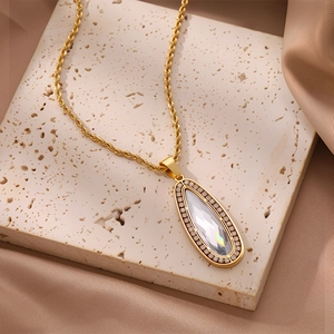 Primer plano de cadena de cordón dorado con colgante de cristal sobre fondo de piedra