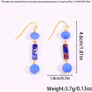 Détail de boucles d'oreilles pendantes avec perles bleu clair et cylindres marbrés