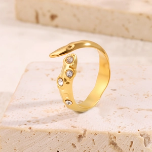 Détail macro d'une bague irrégulière dorée avec quatre pierres de zircone cubique