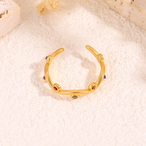 Matte gold leaf ring with rainbow zircon stones on white rock, open adjustable band