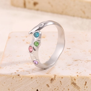 Détail d'une bague vague en acier titane argenté ornée de quatre pierres de zircon colorées