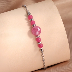 Gros plan de perles de cristal rose et chaîne en acier inoxydable sur fond de soie