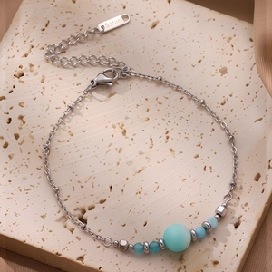 Détail d'un bracelet en acier titane avec perles colorées et étiquette en métal S.stuel