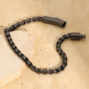 Close-up of gunmetal box chain bracelet with cylinder clasp on stone surface