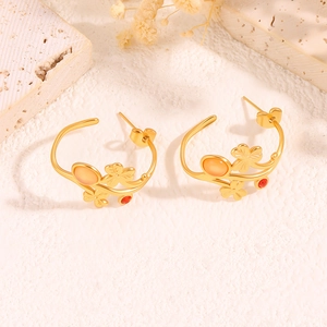 Détail de boucles d'oreilles feuilles dorées en C avec zircons colorés et trèfles