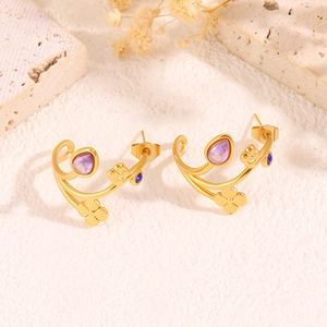 Vue détaillée de boucles d'oreilles trèfle doré avec gemmes violettes et accents bleus