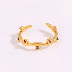 Detail of wavy gold-plated titanium steel ring featuring colorful inlaid crystals