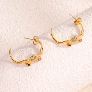 Détail de boucles d'oreilles feuille dorées en C avec pierres précieuses colorées