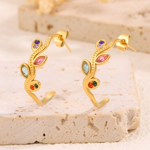 Vue macro de boucles d'oreilles dorées en C avec pierres colorées sur base en pierre