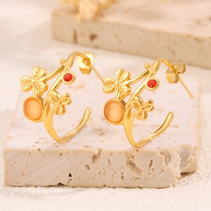 Gros plan de boucles d'oreilles vintage en or avec gemmes rouges et fleurs sur pierre