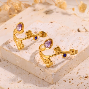 Détail de boucles d'oreilles fleurs dorées avec pierres violettes en poire et bleues