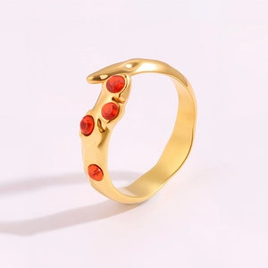 Détail d'une bague dorée irrégulière ornée de quatre petites pierres rouges alignées