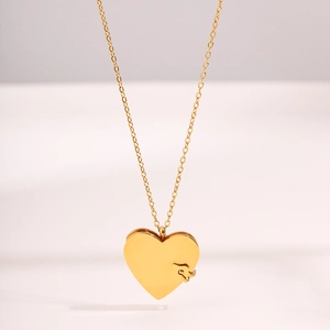 Détail d'un collier médaillon cœur doré poli avec une finition miroir lisse