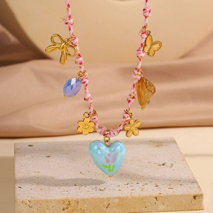 Détail du collier bohème avec cordon rose, papillon doré et pendentif cœur tulipe