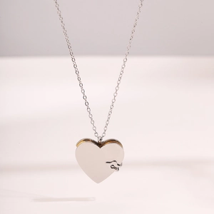 Détail macro du médaillon coeur argenté avec couche dorée et petit pendentif en clé