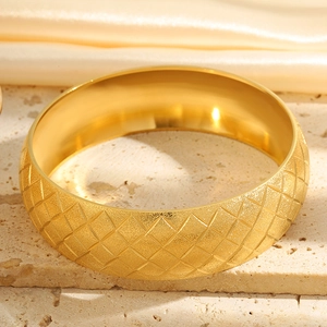 Macro detail of gold-plated wide bangle featuring frosted starry matte finish and grid pattern