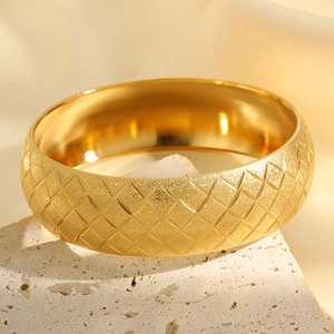 Macro shot of gold star engraved matte finish titanium steel wide cuff bangle jewelry
