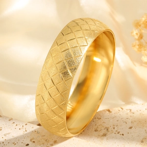 Golden wide bangle with frosted finish and diamond pattern on elegant satin background