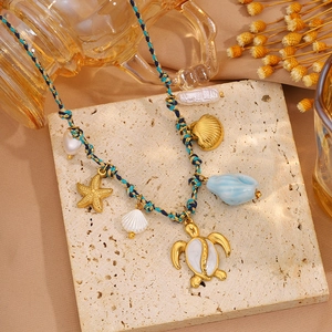 Détail du collier en cordon tisse coloré avec pendentifs étoile de mer et tortue dorés