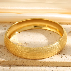 Macro shot of gold matte titanium bangle with textured finish on stone base