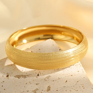 Detail of gold titanium steel bangle with frosted sand finish and five grooved lines