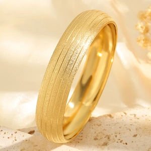 Wide gold titanium steel bangle with frosted finish and five polished grooves shown on stone